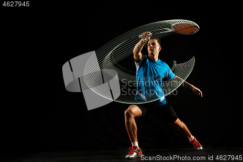 Image of Young male badminton player over balck background