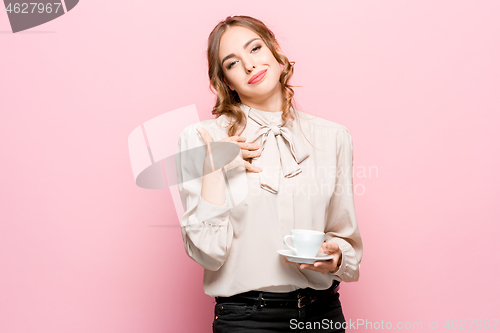 Image of The serious frustrated young beautiful business woman on pink background