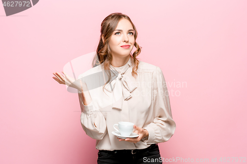 Image of The serious frustrated young beautiful business woman on pink background