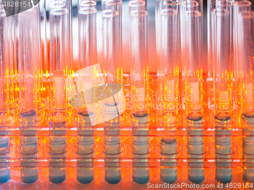 Image of Glass test tubes containing blue liquid on warm orange background.