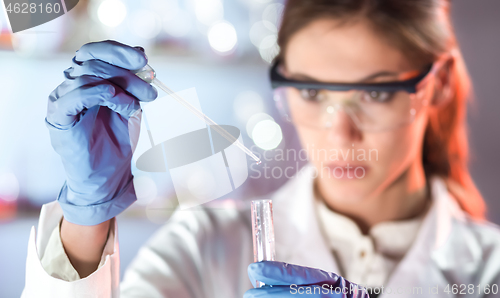 Image of Young scientist pipetting in life science laboratory.