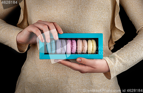 Image of Female hands hold macaroons in gift box