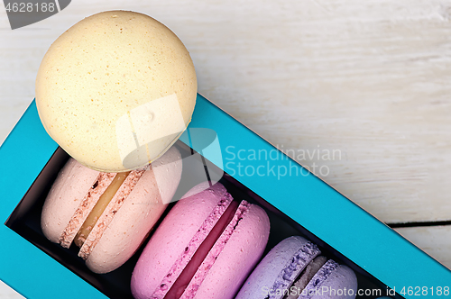 Image of Macaroons in box and one on top 