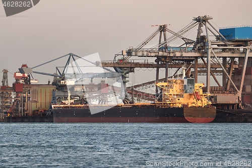 Image of Industrial harbor with rusty structures, bulk carrier ship