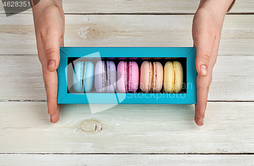 Image of Female hands holding box with macaroons