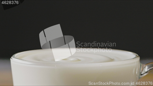 Image of Milk drops drip into a cup with organic milk making splash around a dark background. Slow motion, Full HD video, 240fps, 1080p.