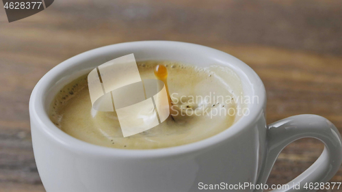 Image of Close-up in a cup of fragrant espresso with foam fall coffee splash on a brown wooden table. Slow motion, Full HD video, 240fps, 1080p.