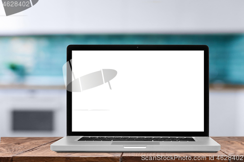 Image of Laptop with blank screen against blurred kitchen interior background.