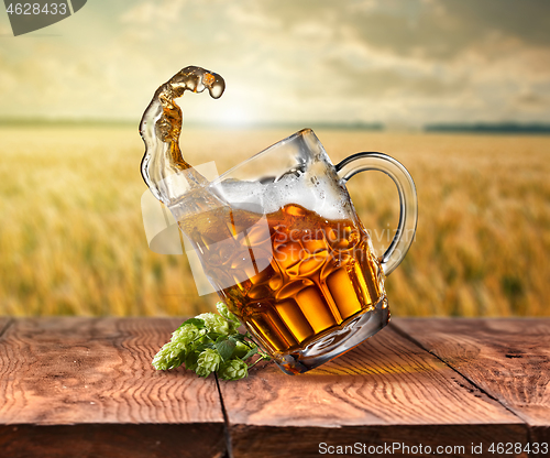 Image of Glass of beer on wooden table with sea on background