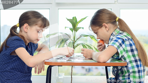 Image of Children at home at the table collect puzzle puzzles