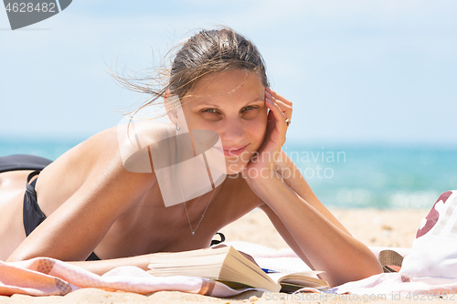 Image of Relaxed girl sunbathes on the beach lying on the sand