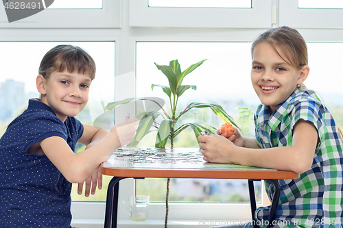 Image of Children assemble a puzzle at home and happily look into the frame