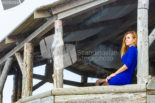 Image of A slender thoughtful girl in a blue dress was sitting in an arbo