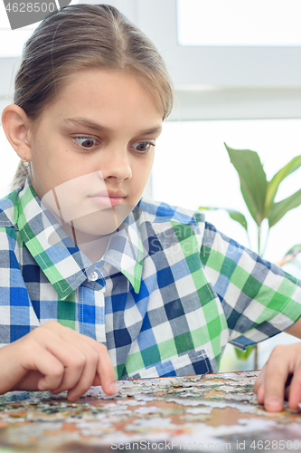 Image of Girl in surprise looks at the puzzle on the table