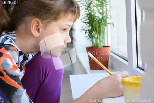 Image of The girl draws thoughtfully and looked out the window