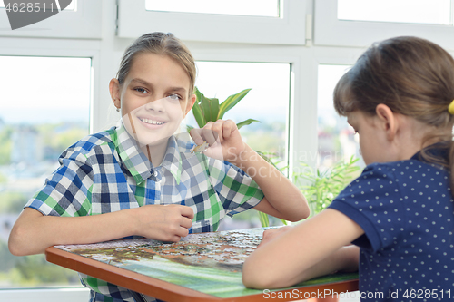 Image of Children assemble a puzzle from puzzles, one of them looked into the frame