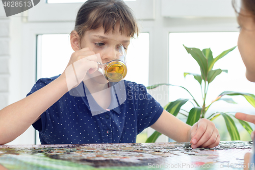 Image of Girl drinks water playing board games at the table