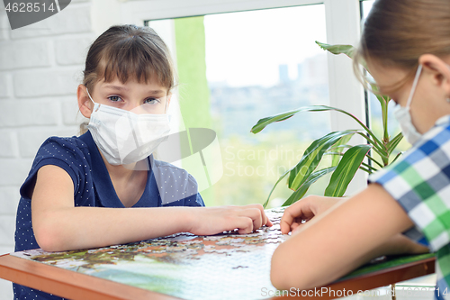 Image of A girl in a medical mask plays board games and looked into the frame.