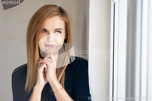 Image of Portrait of a young beautiful girl near a window with natural lighting