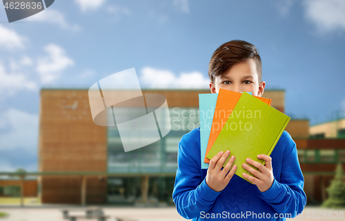 Image of shy student boy hiding behind books over school