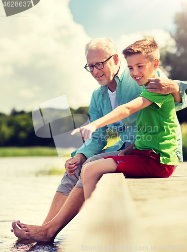 Image of grandfather and grandson sitting on river berth