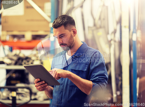 Image of auto mechanic or smith with tablet pc at workshop