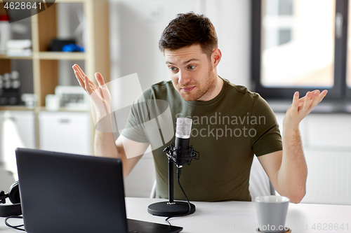 Image of man with laptop and microphone at home office