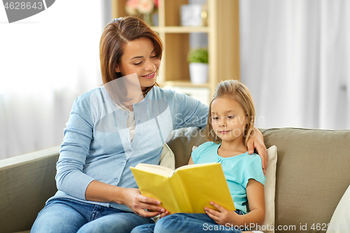 Image of happy girl with mother reading book at home