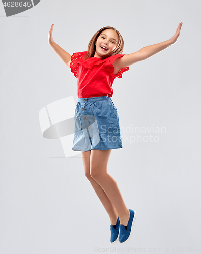 Image of happy smiling girl in red shirt and skirt jumping