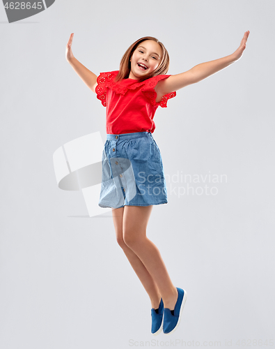 Image of happy smiling girl in red shirt and skirt jumping