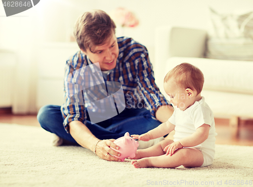 Image of happy father with baby and piggy bank at home