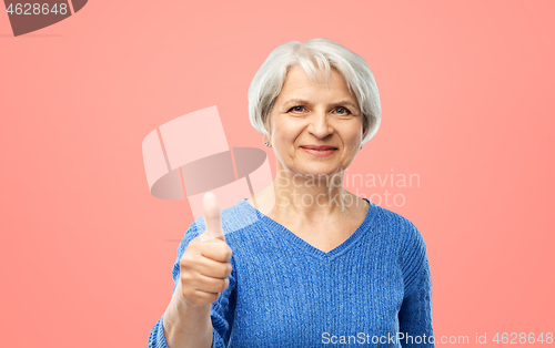 Image of smiling senior woman r showing thumbs up over pink
