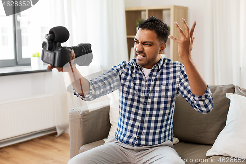 Image of male video blogger with camera blogging at home