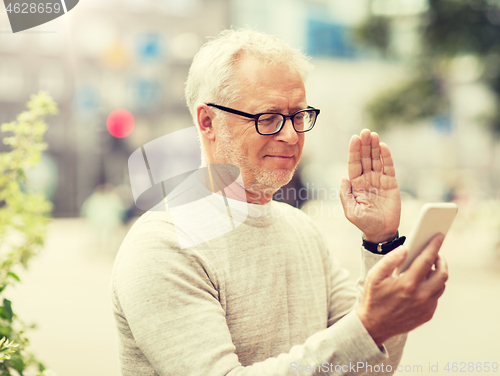 Image of senior man having video call on smartphone in city