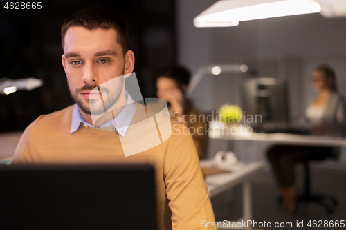 Image of man with computer working late at night office