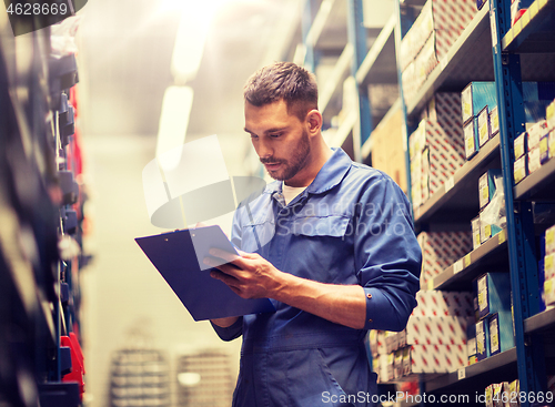 Image of auto mechanic with clipboard at car workshop