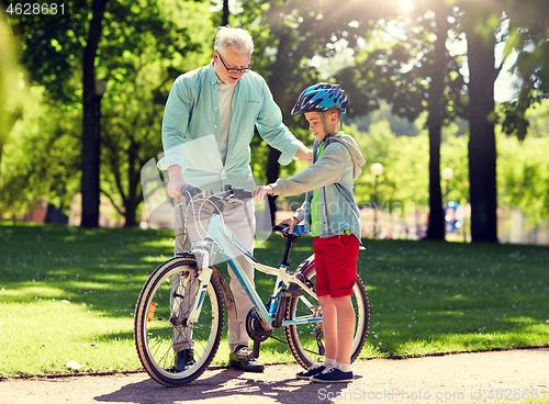 Image of grandfather and boy with bicycle at summer park