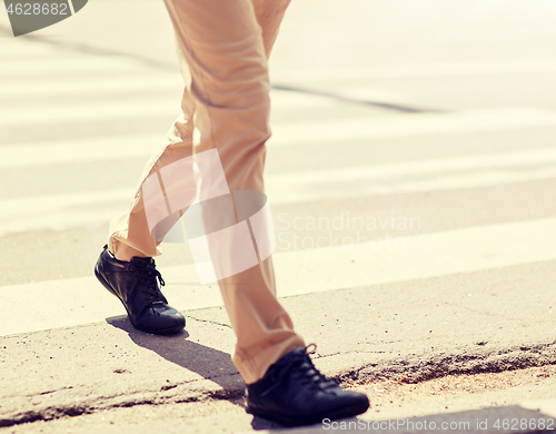 Image of senior man walking along city crosswalk