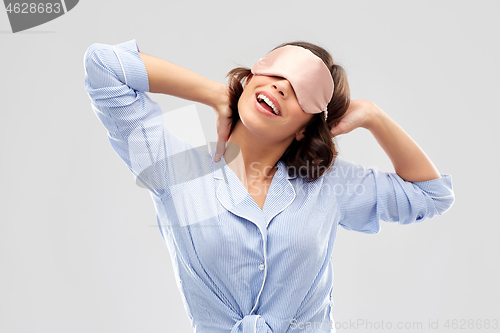 Image of happy young woman in pajama and eye sleeping mask