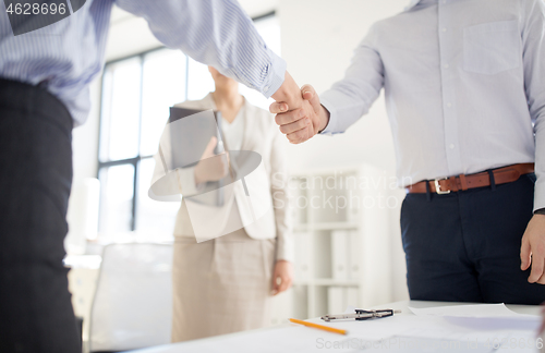 Image of close up of businessmen making handshake at office