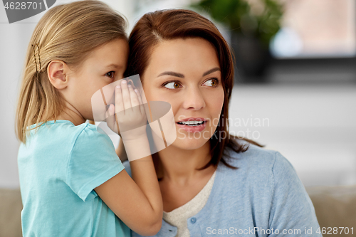 Image of daughter whispering secret to mother at home