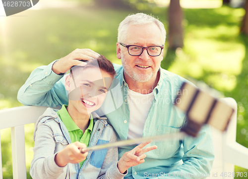 Image of old man and boy taking selfie by smartphone