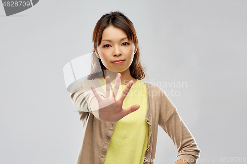 Image of young asian woman showing stop gesture