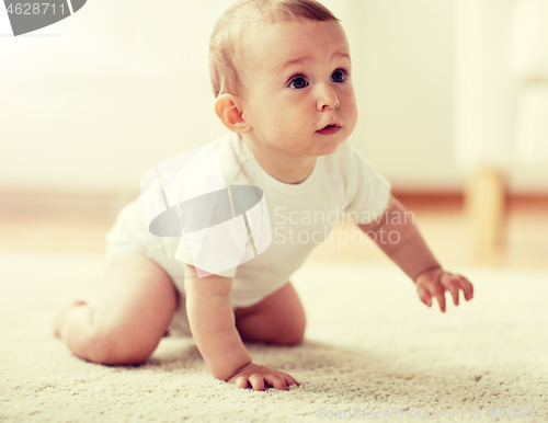 Image of little baby in diaper crawling on floor at home