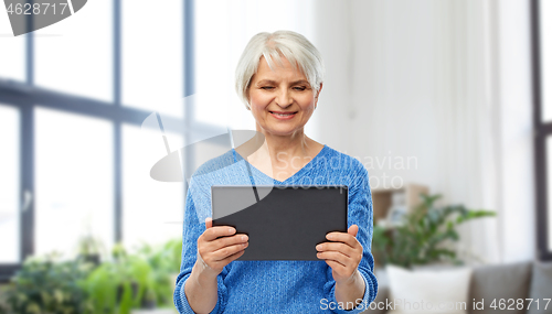 Image of senior woman using tablet computer at home