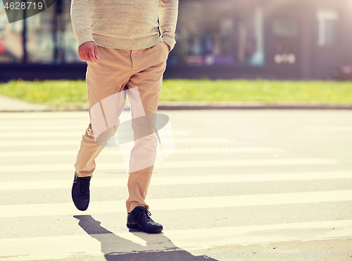 Image of senior man walking along city crosswalk