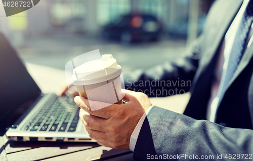 Image of senior businessman with laptop and coffee outdoors