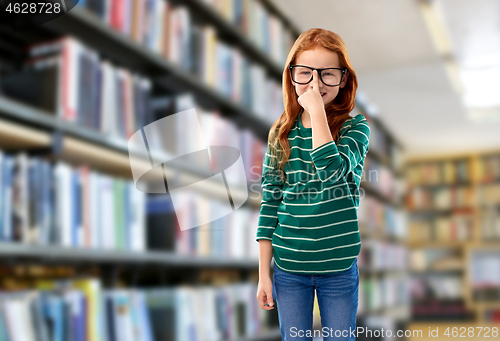 Image of cute red haired student girl in glasses at library