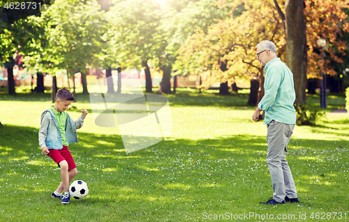 Image of old man and boy playing football at summer park