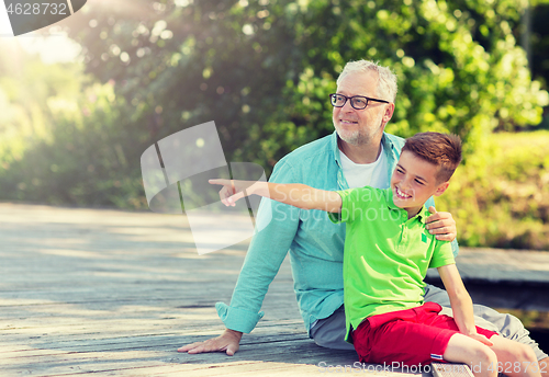 Image of grandfather and grandson sitting on river berth